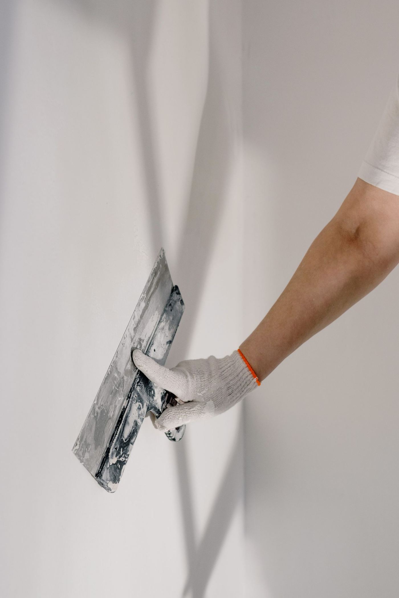 Contractor repairing water-damaged ceiling drywall with fresh joint compound