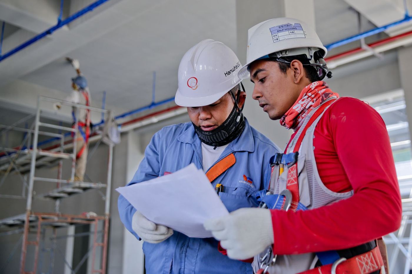 Two restoration technicians in hard hats reviewing a job plan on site